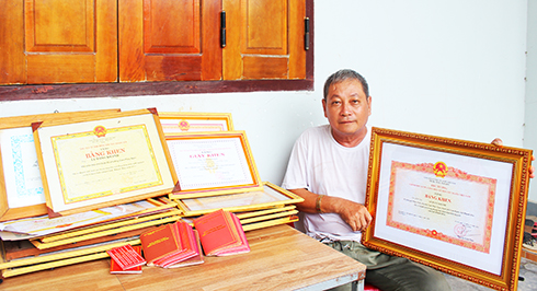 Ông Lê Đăng Khánh bên bộ sưu tập bằng khen của gia đình trong phong trào hiến máu tình nguyện