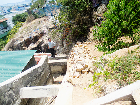 Đá chẻ chất đống lỏng lẻo dưới chân kè, dễ lăn xuống mái nhà người dân nếu có mưa to