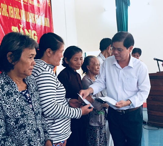 Ông Nguyễn Tấn Tuân trao quà cho các hộ gia đình