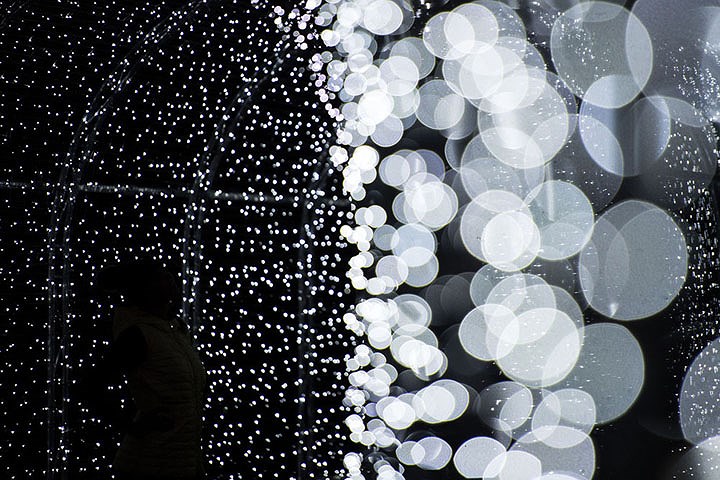 Một phụ nữ (trái) tạo dáng chụp ảnh trong một “đường hầm” ánh sáng tại sự kiện Kew ở London (Anh) vào hôm 21/11.