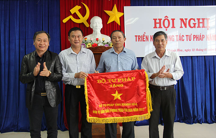 Ông Nguyễn Đắc Tài (bìa trái) trao cờ thi đua ngành Tư pháp cho đại diện Sở Tư pháp. 