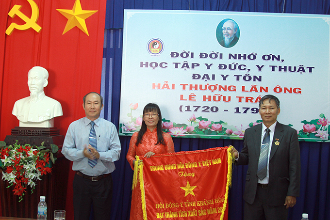 Lãnh đạo Sở Nội vụ (trái) thay mặt Trung ương Hội Đông y Việt Nam trao cờ thi đua xuất sắc cho Hội Đông y tỉnh 