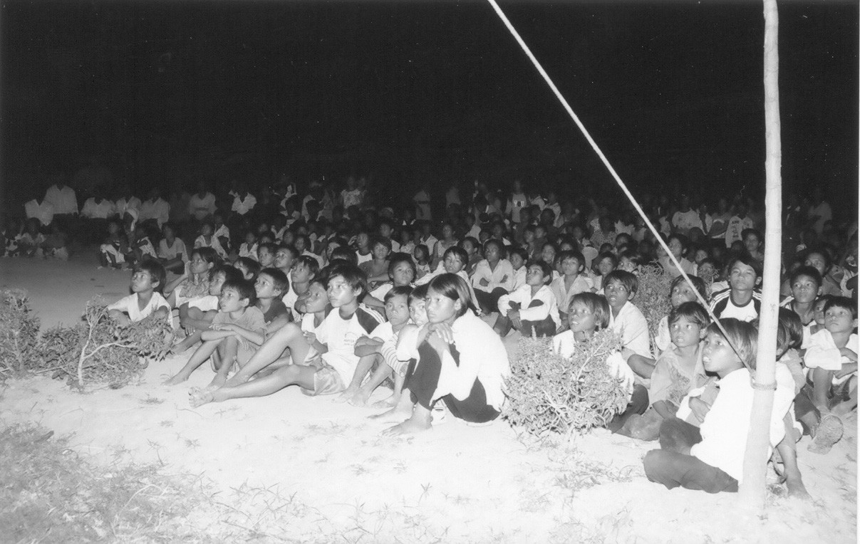 Cảnh người dân ngồi xem phim trên nền đất một thời.