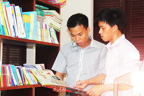 Thầy giáo Lê Xuân Quyết (bên trái) bàn giao sổ, sách dạy học lại cho thầy giáo Nguyễn Hữu Tình.