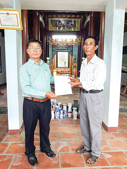 Leader of Khanh Hoa Provincial Branch of Archives (left) offering recognition certificate of precious and rare document to member of Managing Committee of Dong Nhon Communal House (Vinh Trung Commune, Nha Trang)