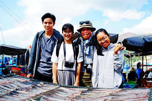 Photographer Ba Han posing with three selected students of Nha Trang
