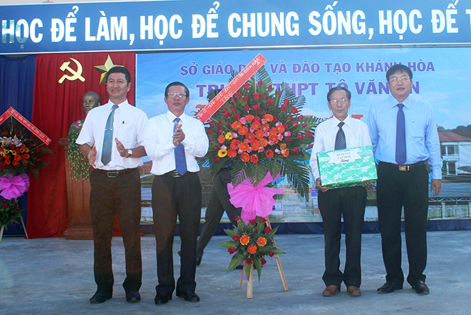 ÔngTrần Ngọc Thanh (thứ 2 từ trái qua) tặng lẵng hoa chúc mừng thầy và trò Trường THPT Tô Văn Ơn.