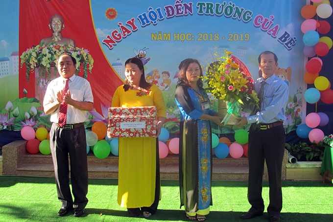Ông Nguyễn Chuyện (bìa phải) cùng lãnh đạo huyện trao quà cho ban giám hiệu nhà trường