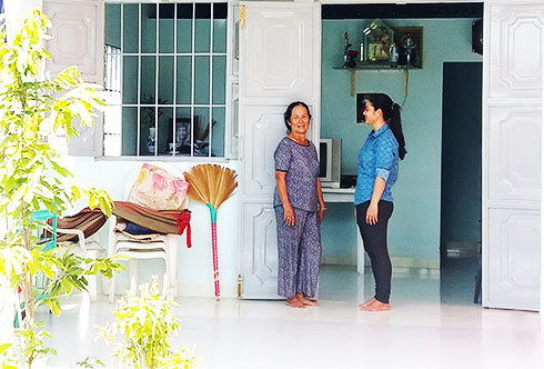 Bà Lê Thị Bán (bên trái) chia sẻ niềm vui nhà mới với cộng tác viên công tác xã hội của xã. 