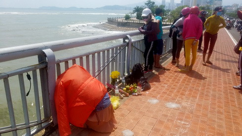 Bạn gái người thanh niên nhảy cầu đau buồn ngồi trên cầu chờ tin từ lực lượng cứu hộ, cứu nạn.