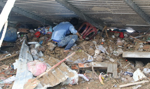 Một người dân cặm cụi tìm lại tài sản trong đống đổ nát.