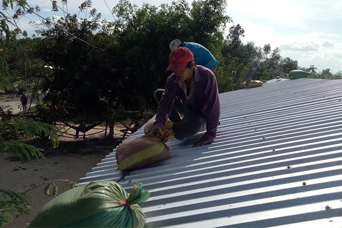 Người dân xã Khánh Đông, Khánh Vĩnh dùng bao cát giằng mái nhà chống bão