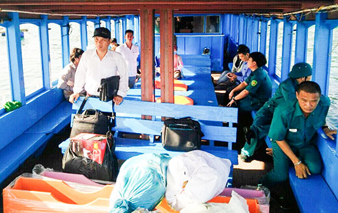 Đoàn công tác của xã Cam Bình đi đò qua đảo Bình Hưng giải quyết thủ tục hành chính.