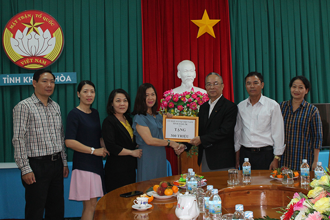 Ông Lê Xuân Sương - Phó Chủ tịch Thường trực UBMTTQ Việt Nam tỉnh Đắk Lắk (bìa phải) trao tượng trưng tiền hỗ trợ khắc phục bão số 8