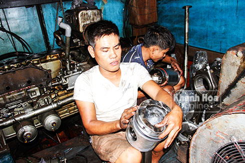 Một thợ máy đang thay vòng bạc cho piston của máy tàu cá.