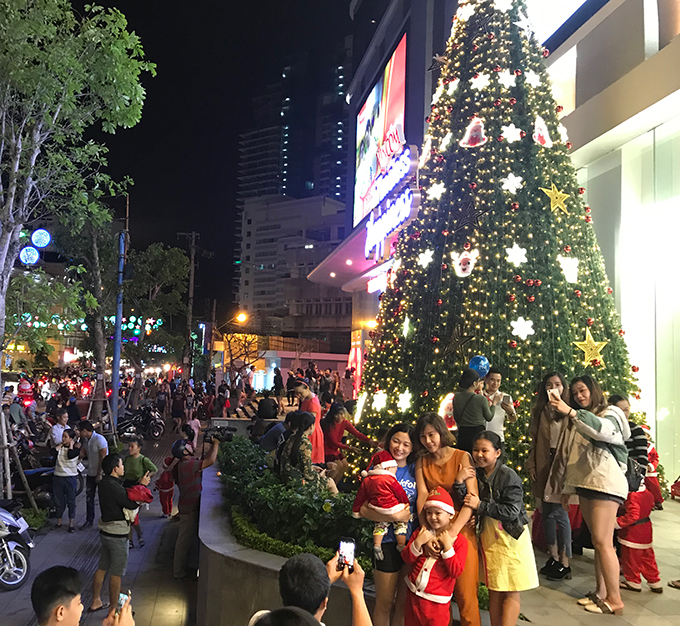 People posing for photos with Christmas decoration at Vincom Plaza on Le Thanh Ton Street….