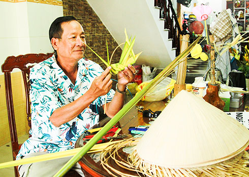 Nghệ nhân Nguyễn Yến đang thao tác làm một chú cào cào lá dừa.
