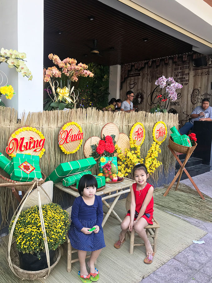 Children posing for photo with Lunar New Year decorations at a café on Yersin Street