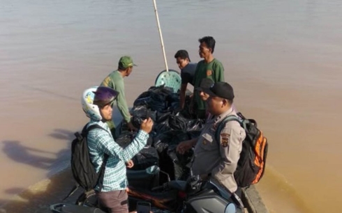 Nhân viên kiểm soát bầu cử cùng cảnh sát địa phương dùng thuyền đi phân phối hậu cần cho các điểm bầu cử bị lũ lụt tại tỉnh Jambi. Nguồn: Ủy ban bầu cử tỉnh Jambi/ Antaranews