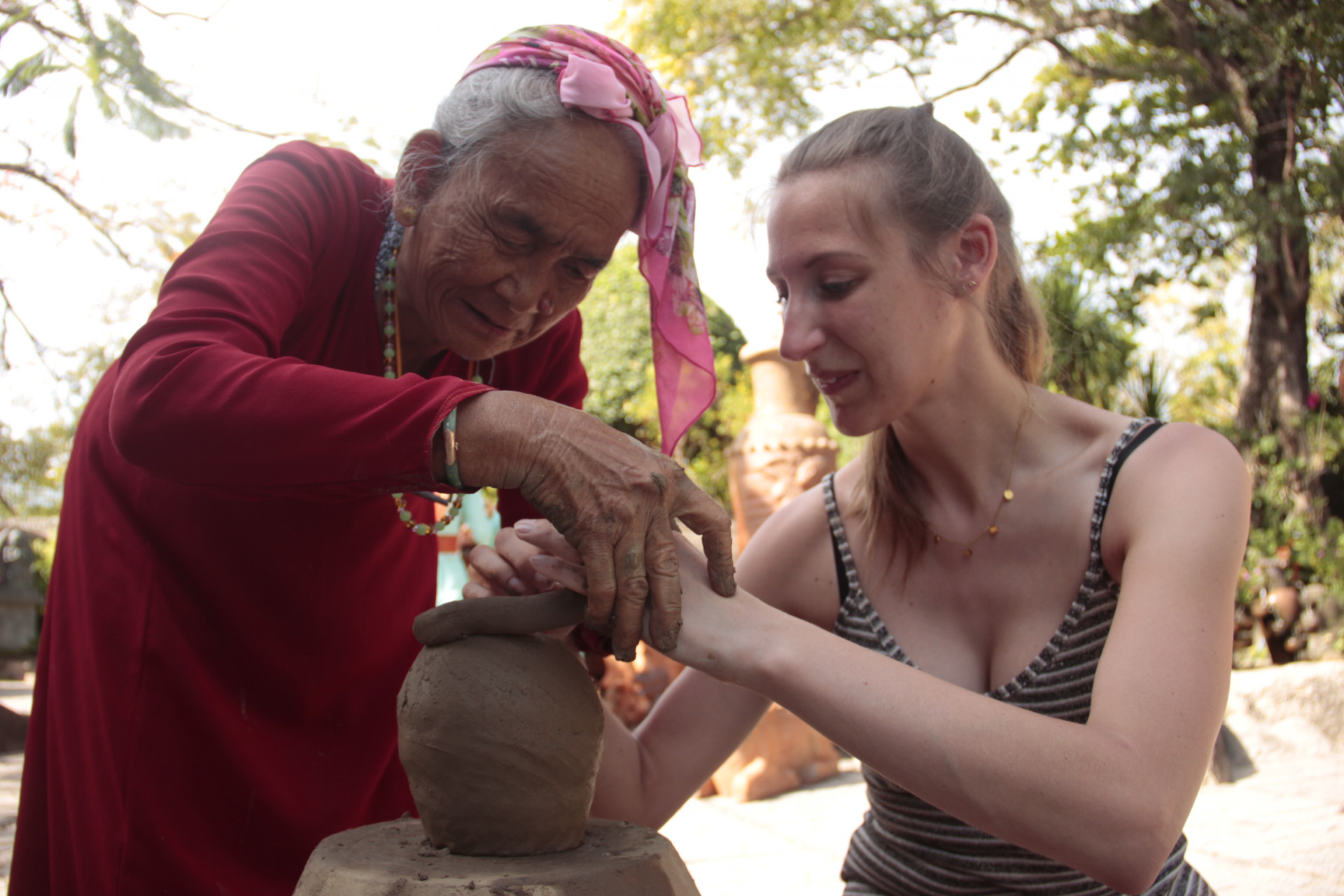 Artisan Truong Thi Gach teaching foreign tourist to make pottery item