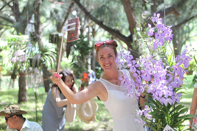 Một du khách nước ngoài tạo dáng bên các giỏ hoa lan tại hội thi.