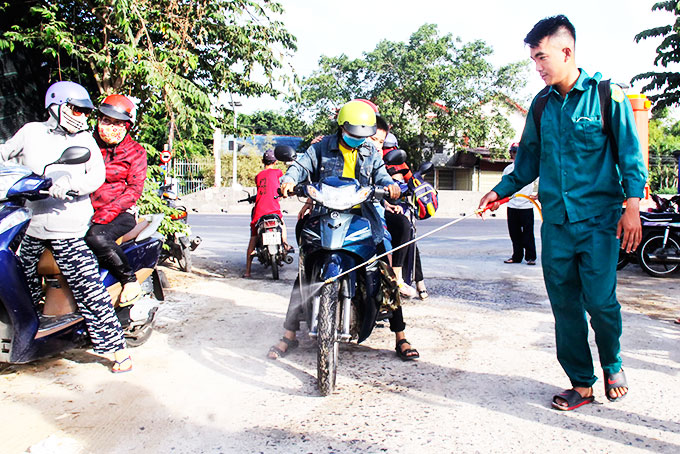 Lực lượng chức năng phun thuốc khử trùng trên đường ra vào thôn Như Xuân 1, xã Vĩnh Phương. 