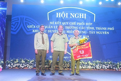 Đại diện Cục Quản lý thị trường tỉnh Khánh Hòa (bên trái) trao cờ luân lưu đăng cai tổ chức hội nghị sơ kết năm 2020 cho đại diện Cục Quản lý thị trường tỉnh Kon Tum.