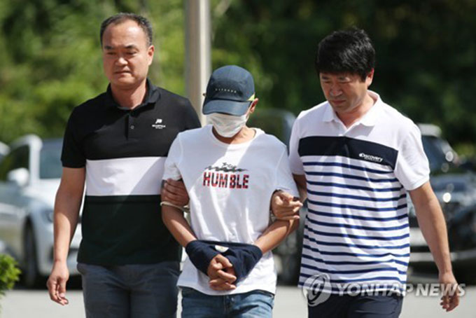 Nghi phạm đánh vợ Việt (giữa) bị áp giải ra tòa án thành phố Gwangju, tỉnh Jeollan Nam hôm 8/7. Ảnh: Yonhap.