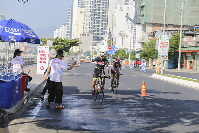 Tình nguyện viên tiếp nước cho các tay đua trên đường chạy đạp xe.
