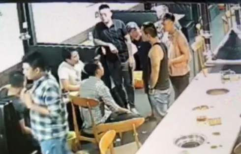 Ông Hòa (áo trắng) bị côn đồ vây quanh.