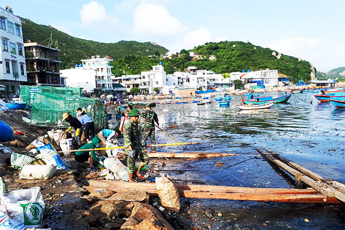 Phụ nữ Cam Bình phối hợp với bộ đội vớt rác thải trên biển Bình Ba.