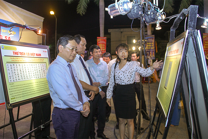 Ông Nguyễn Đắc Tài và các đại biểu đi xem tư liệu, hình ảnh được giới thiệu tại triển lãm.