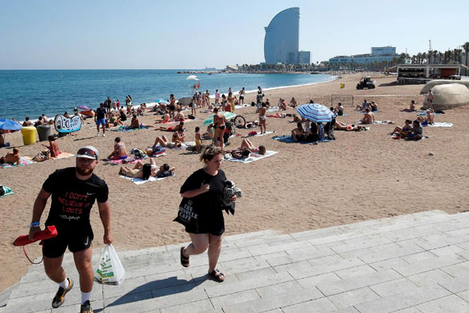 Mọi người rời khỏi bãi biển Sant Sebastia sau khi cảnh sát tìm thấy một thiết bị nổ trong nước (Ảnh: Reuters)