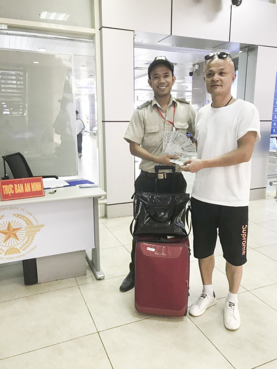 Đại diện an ninh sân bay trao trả tài sản bị bỏ quên cho hành khách Zhou Guixing, Quốc tịch Trung Quốc.