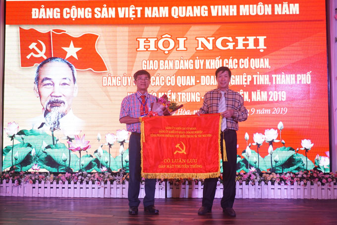 Ông Lương Kiên Định (bìa phải) trao cờ luân lưu cho ông Hồ Văn Hùng.