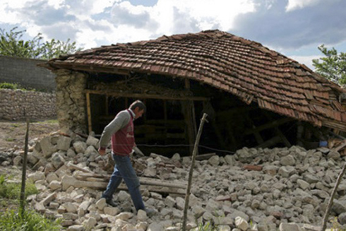 Một người đàn ông đi bộ bên ngoài tòa nhà bị phá huỷ sau trận động đất tấn công khu vực ở Floq, Albania vào ngày 1/6/2019 (Ảnh: Reuters).