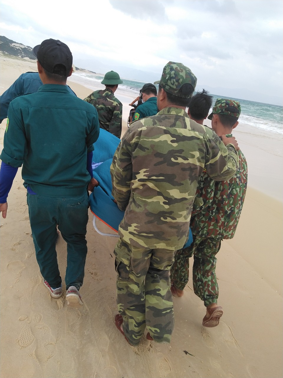 Các lực lượng đưa thi thể nạn nhân vào bờ.