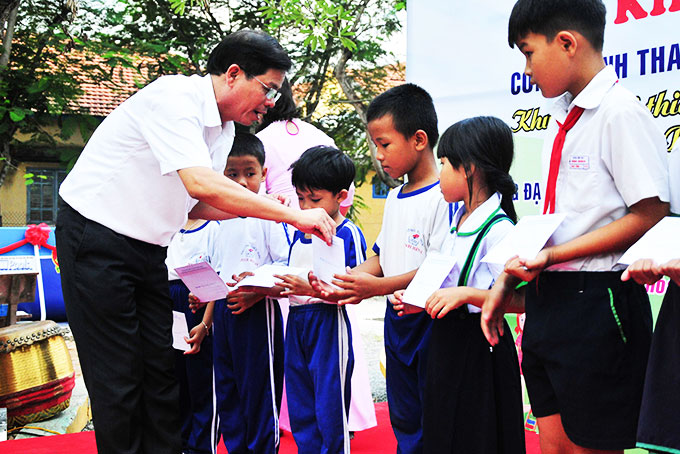 Ông Nguyễn Tấn Tuân trao học bổng cho các học sinh khó khăn.