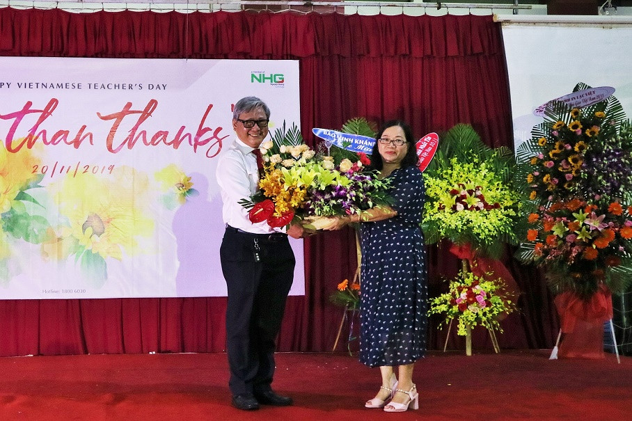 Đại diện hội cha mẹ học sinh tặng hoa cho hiệu trưởng nhà trường. 