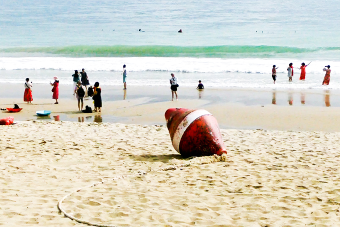 Sớm thu dọn phao trôi trên bờ biển