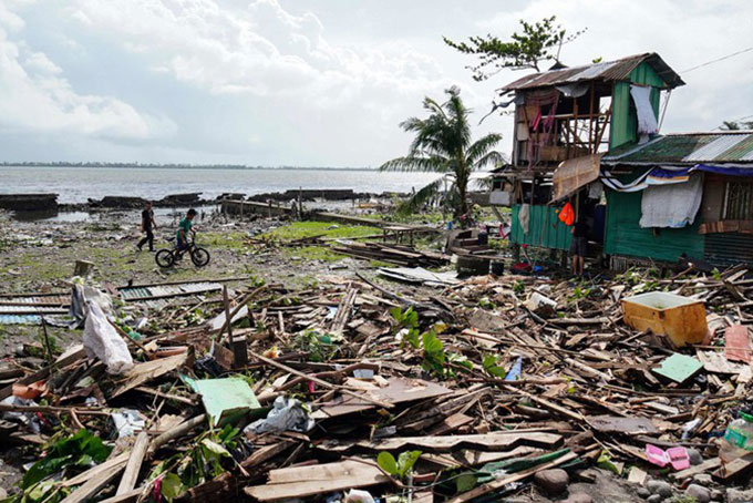 Người dân đi qua một ngôi nhà bị tàn phá ở tỉnh Leyte, miền trung Philippines hôm 25/12. Ảnh:  AFP