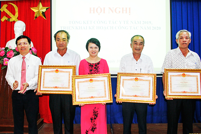 Thừa ủy nhiệm của Thủ tướng Chính phủ, lãnh đạo Sở Y tế (bìa trái) trao cờ thi đua cho Trung tâm Y tế huyện Diên Khánh.