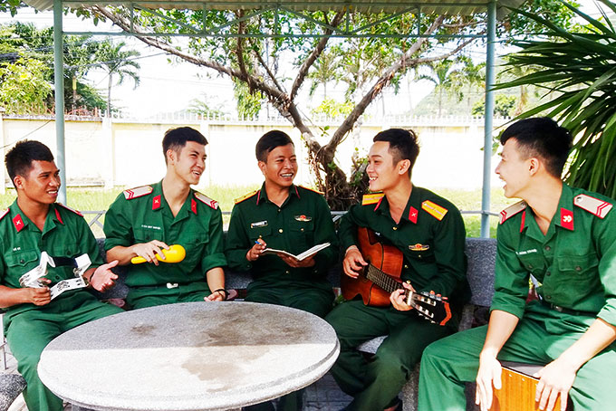 Thiếu úy Cao Trung Nguyên (ngồi giữa) cùng các thành viên tập bài hát mới do anh sáng tác.
