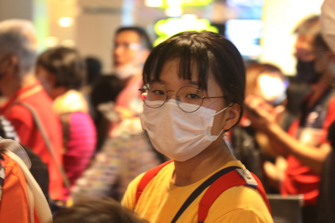 Một bé gái người Thái Lan đeo khẩu trang đề phòng virus corona đang đợi làm thủ tục nhập cảnh cùng người thân