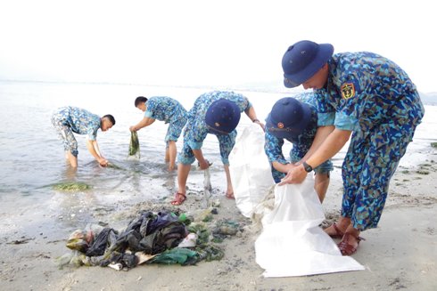 Các cán bộ, chiến sĩ thu gom rác làm sạch bãi biển.
