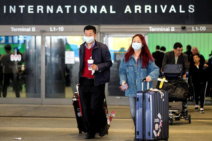  Hành khách đeo khẩu trang để phòng lây nhiễm virus corona khi đến sân bay quốc tế ở Los Angeles, Mỹ. Ảnh: Reuters.