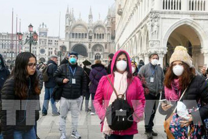 Khách du lịch đeo khẩu trang phòng dịch Covid-19 tại Venice, Italy ngày 25/2. Ảnh: AFP/TTXVN