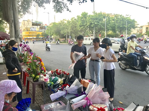 Khách hàng chọn mua hoa trên tại một điểm kinh doanh bên lề đường