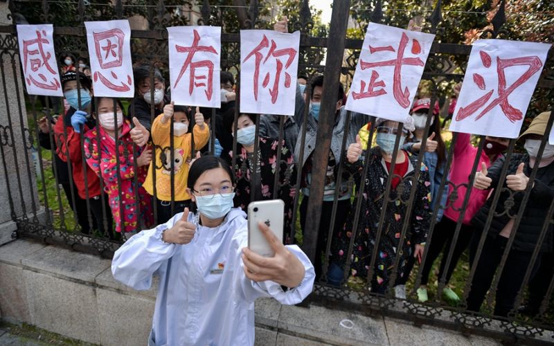 Một nữ nhân viên y tế chụp ảnh kỷ niệm với người dân Vũ Hán trước khi rời đi. Tấm biểu ngữ sau lưng cô mang ý nghĩa  &quot;Cảm ơn có bạn, Vũ Hán &quot;. Ảnh: Nhật báo Trường Giang.