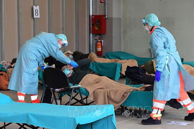 Nhân viên y tế điều trị cho bệnh nhân mắc Covid-19 tại một bệnh viện dã chiến ở Lombardy, Italy ngày 13/3/2020. Ảnh: AFP/TTXVN.